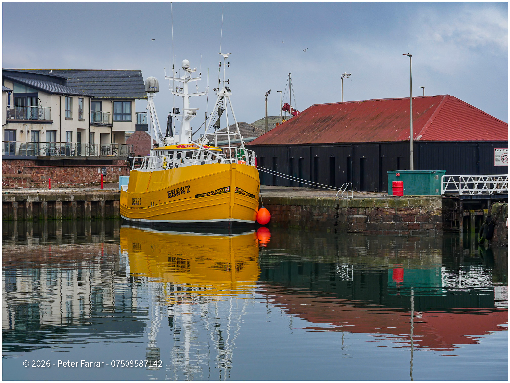 Yellow boat floating in a calm bay near Broughty Ferry, Scotland, with its reflection visible in the water.